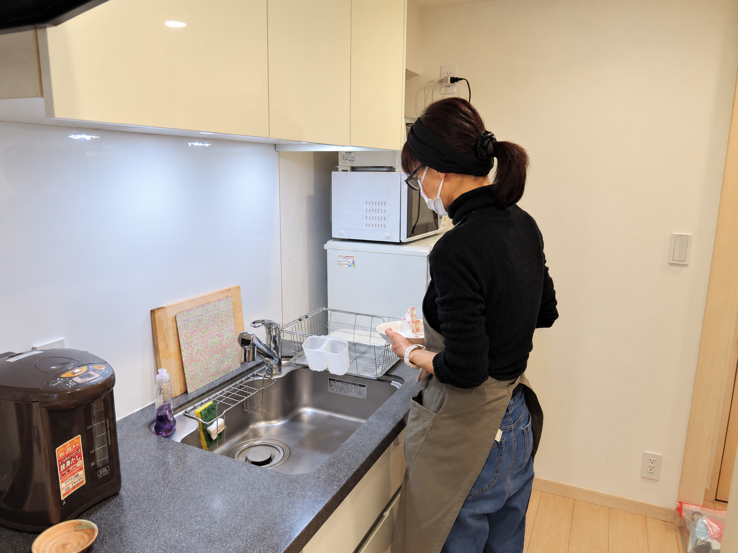 お客様宅のキッチンで、食器を扱いながら家事をするスタッフ