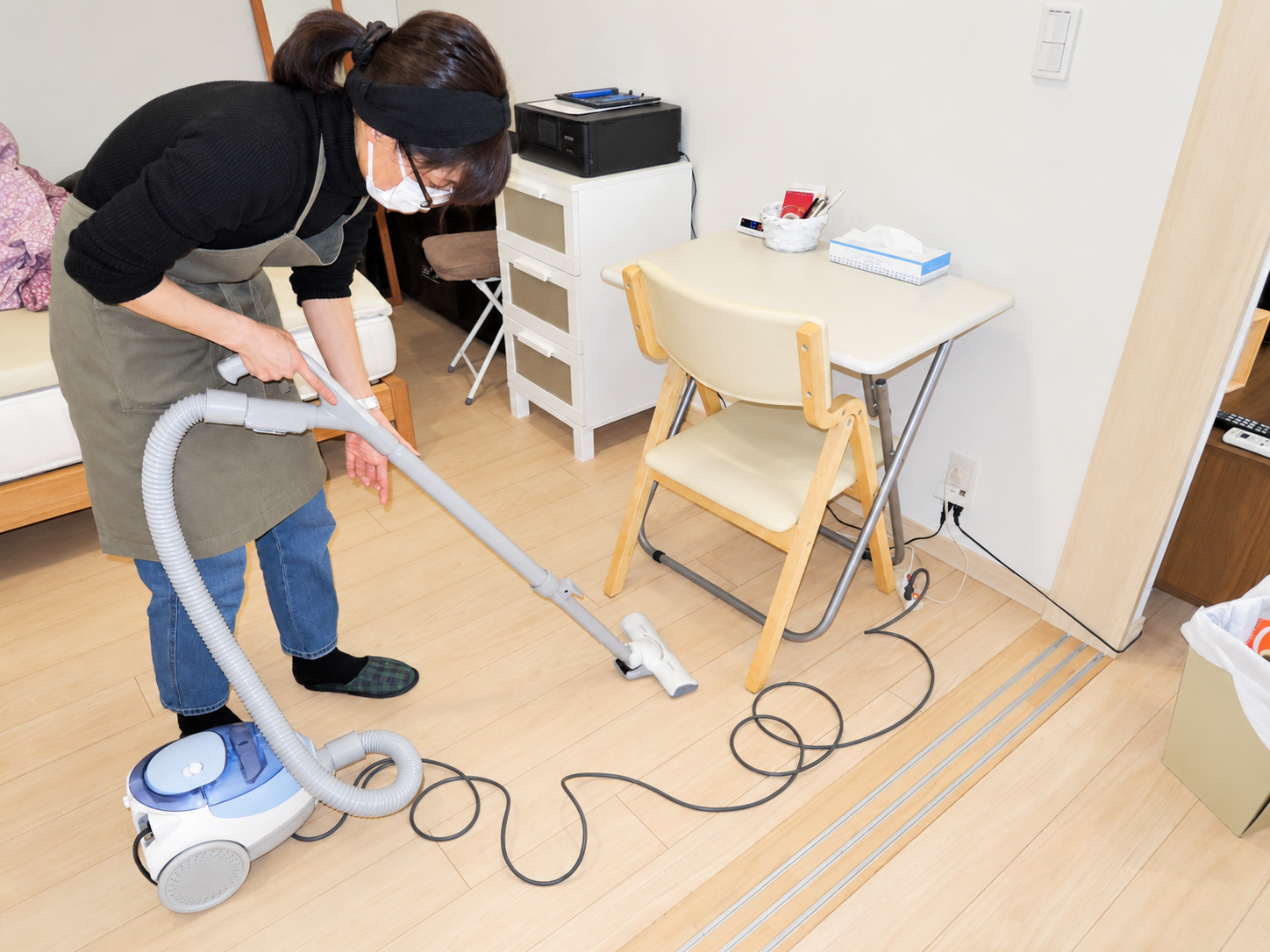 お客様宅の食卓まわりで掃除機をかけるスタッフ